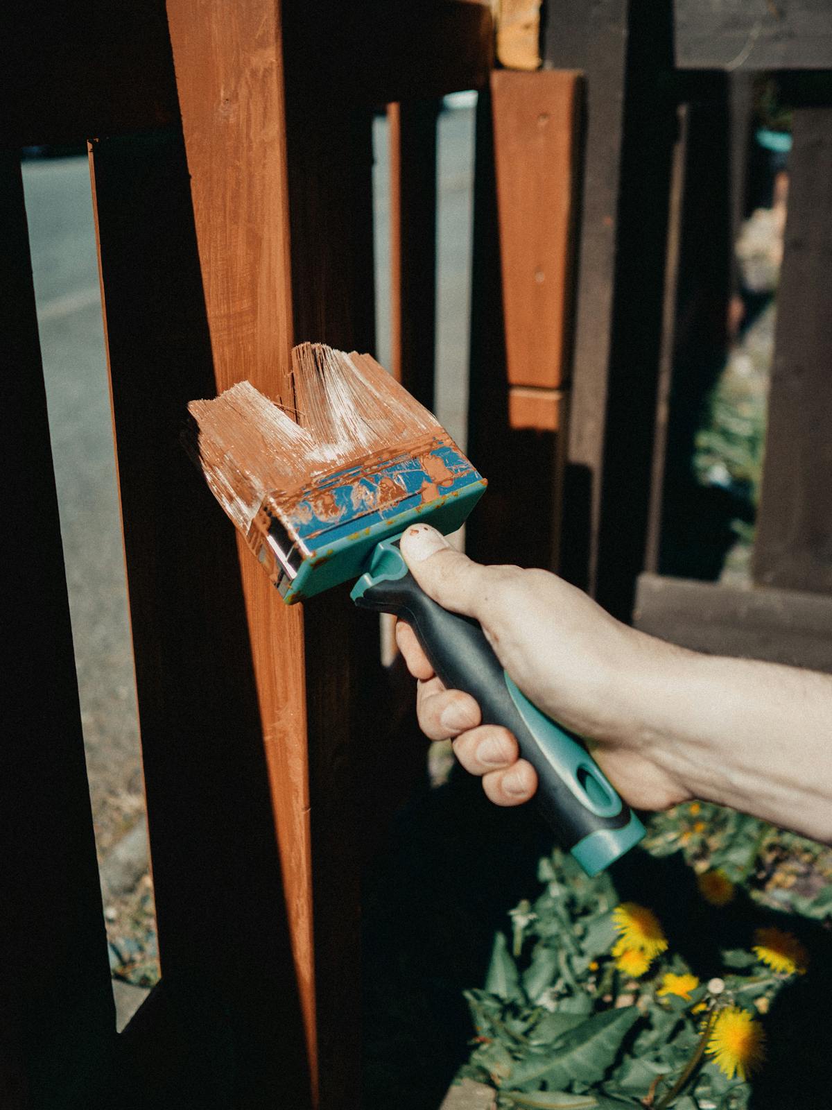 Hand painting wooden decking with a brush during a yearly stain refresh